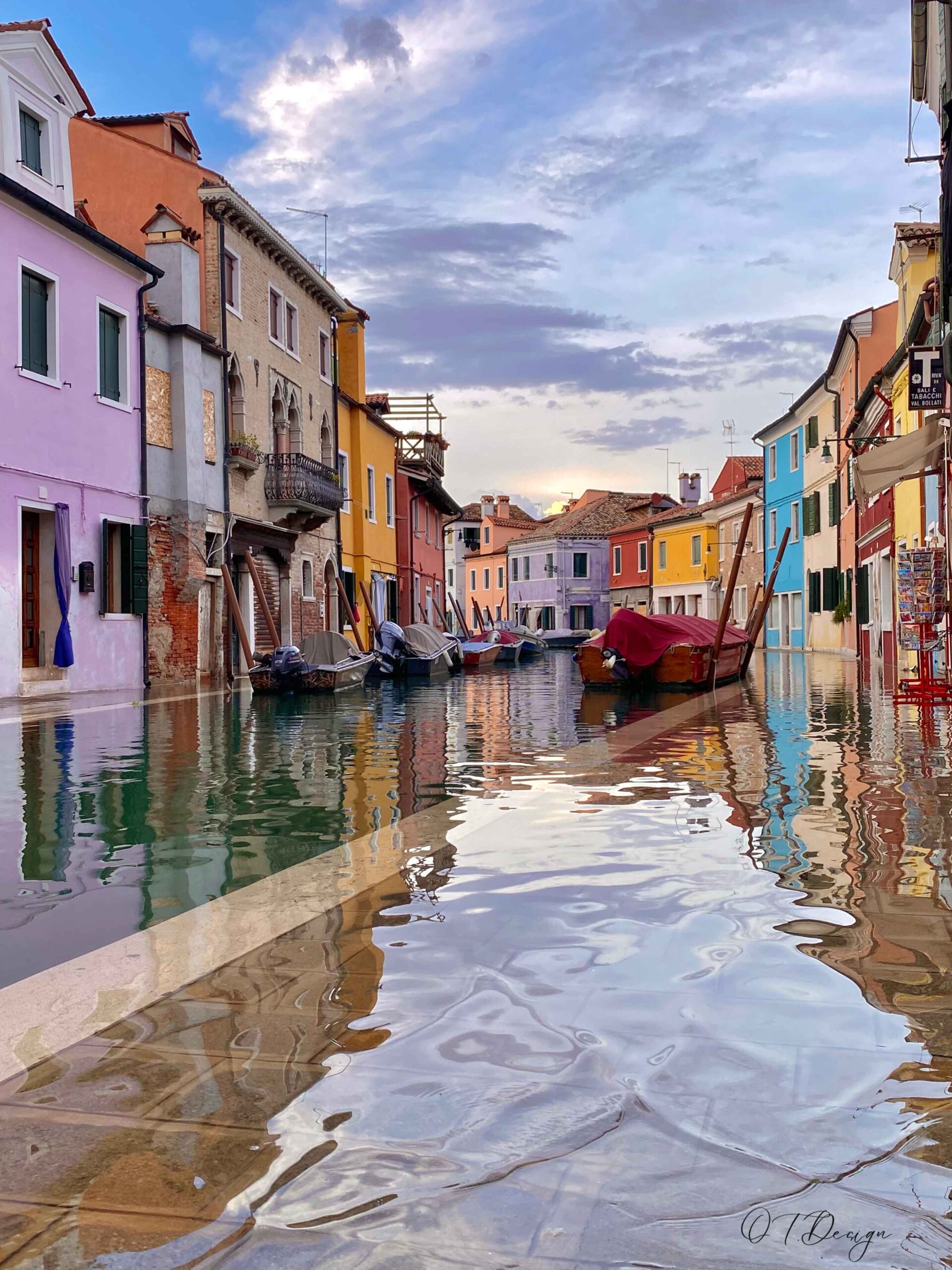 Reflections in the water in time of "Acqua Alta" in the colorful island  of Burano, Italy